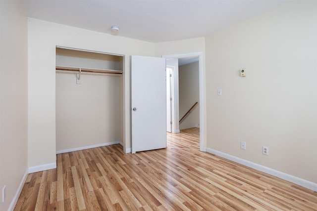 unfurnished bedroom with light wood-style floors, baseboards, and a closet
