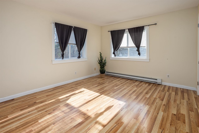 spare room featuring baseboards, a baseboard heating unit, and light wood-style flooring