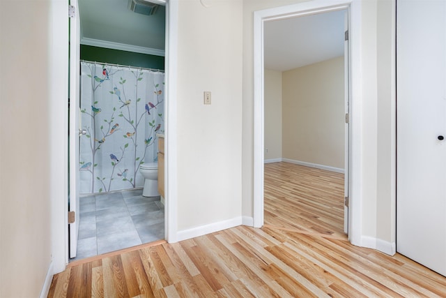 interior space with baseboards, ornamental molding, light wood finished floors, and visible vents