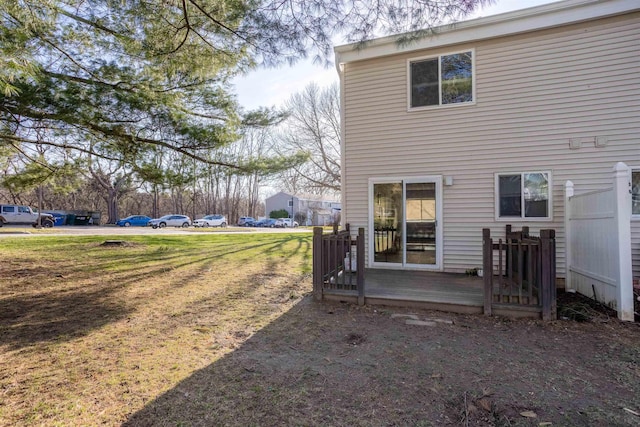 back of property with a lawn and a deck