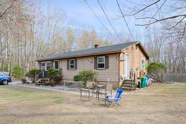 ranch-style home featuring fence, a chimney, and a shingled roof