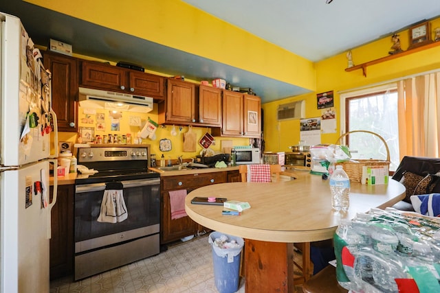 kitchen with brown cabinets, a sink, white appliances, light countertops, and under cabinet range hood