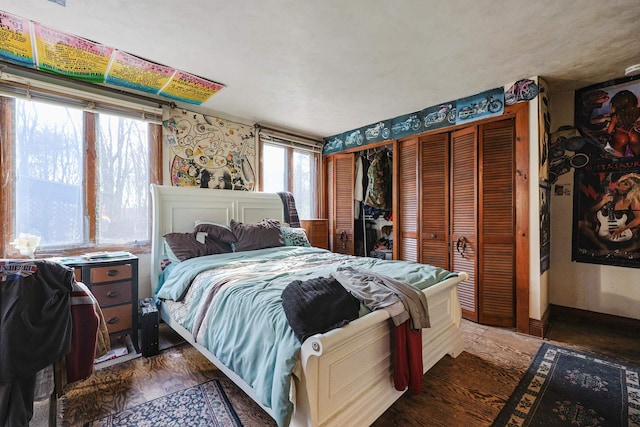 bedroom featuring multiple closets, wallpapered walls, and wood finished floors