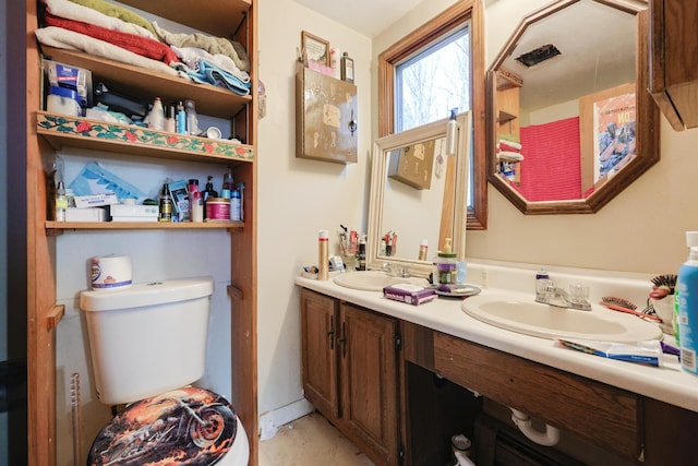 bathroom with double vanity, a sink, and toilet