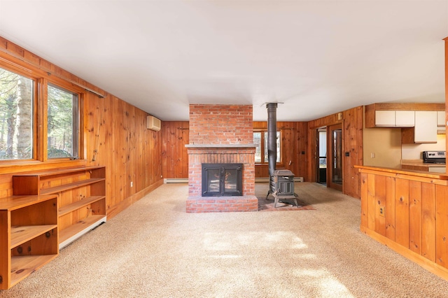 unfurnished living room with wood walls, carpet flooring, and a wood stove