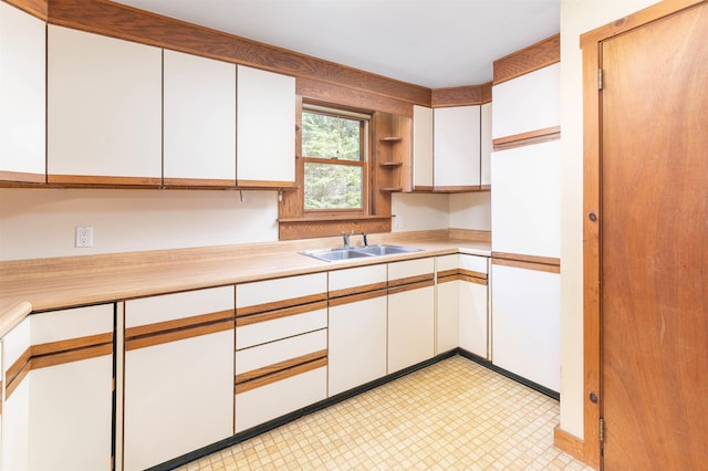kitchen with a sink, open shelves, white cabinets, and light countertops