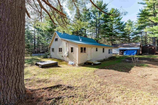 exterior space with a storage shed, an outdoor structure, a chimney, and metal roof