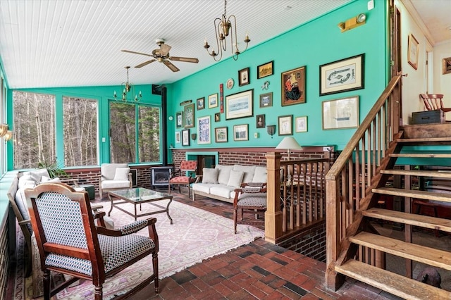 living area with stairway, brick floor, and ceiling fan with notable chandelier