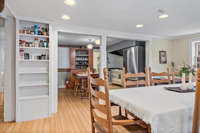 dining space with recessed lighting, bar, and light wood-type flooring