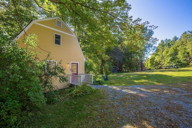 view of side of property featuring a lawn and a gambrel roof