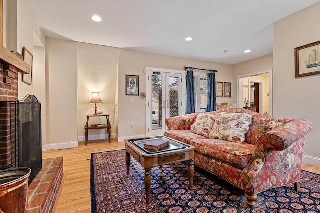 living room with recessed lighting, light wood finished floors, and a brick fireplace