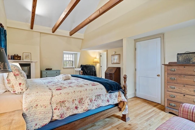 bedroom with lofted ceiling with beams and wood finished floors
