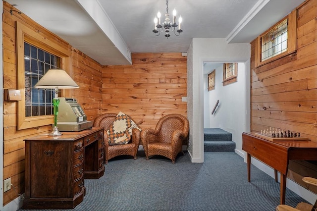 sitting room featuring an inviting chandelier, stairway, carpet floors, baseboards, and wooden walls