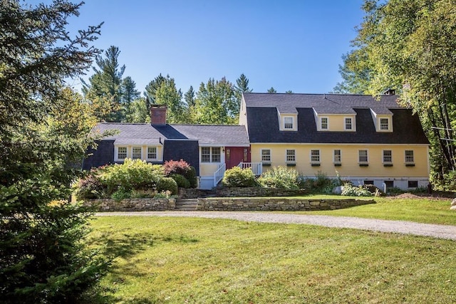 view of front of property featuring roof with shingles, a chimney, and a front yard