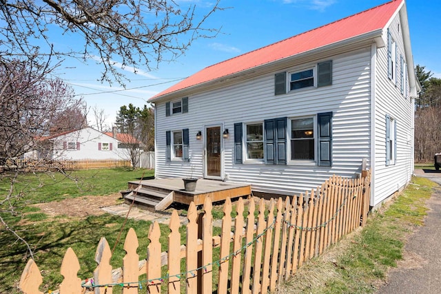 view of front of property featuring fence, a front lawn, and metal roof