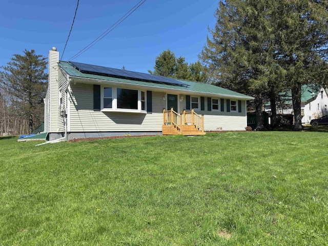 view of front of property featuring solar panels, a front lawn, and a chimney