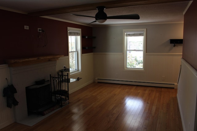 unfurnished living room featuring a baseboard radiator, ceiling fan, a wainscoted wall, and hardwood / wood-style floors