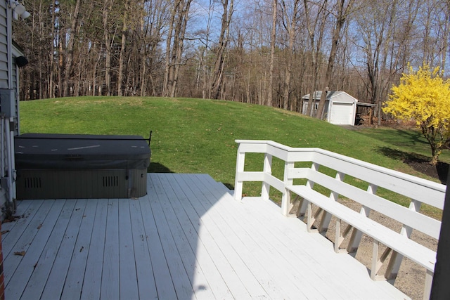 wooden terrace with a hot tub, a yard, and an outbuilding