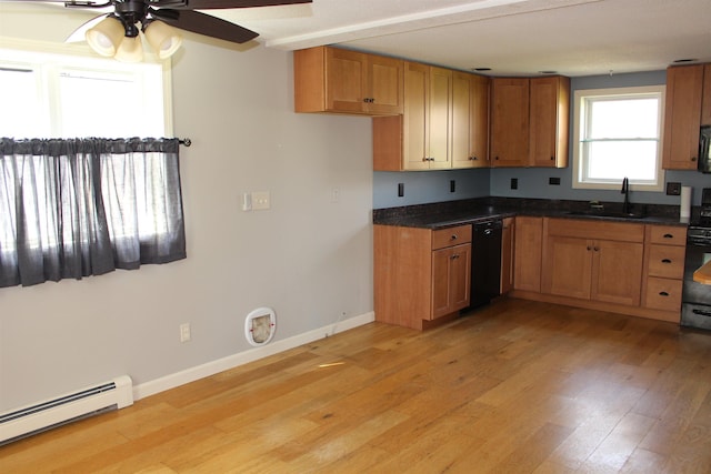 kitchen with a ceiling fan, dark countertops, a baseboard heating unit, and a sink