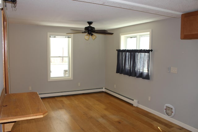 spare room with baseboards, baseboard heating, a ceiling fan, and light wood-type flooring
