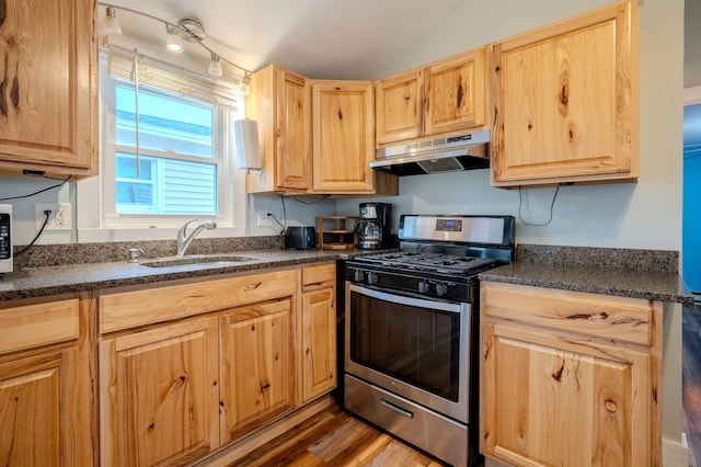 kitchen with under cabinet range hood, stainless steel range with gas stovetop, a sink, and light brown cabinets