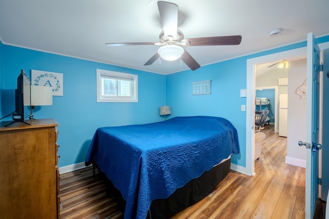 bedroom with a ceiling fan, crown molding, wood finished floors, baseboards, and freestanding refrigerator