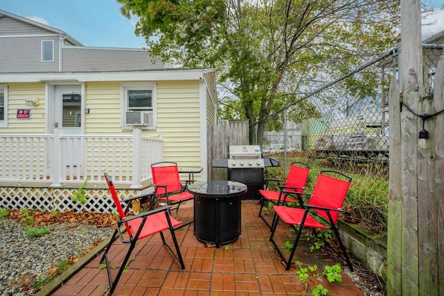 view of patio featuring a fire pit, fence, a wooden deck, and a grill