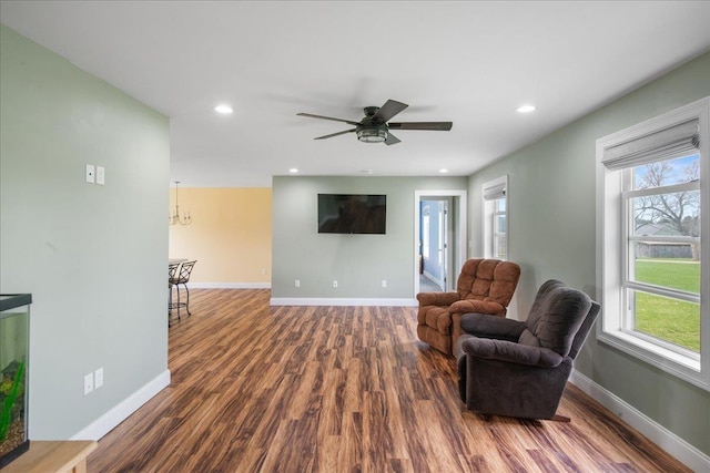 sitting room with dark wood-style flooring, baseboards, recessed lighting, and ceiling fan with notable chandelier