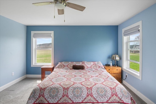 carpeted bedroom featuring baseboards, multiple windows, and ceiling fan