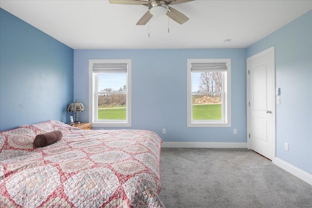 carpeted bedroom featuring baseboards, multiple windows, and ceiling fan