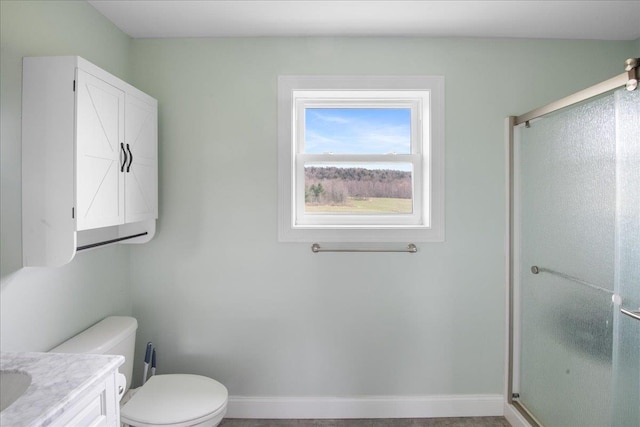 bathroom featuring vanity, baseboards, toilet, and a shower stall