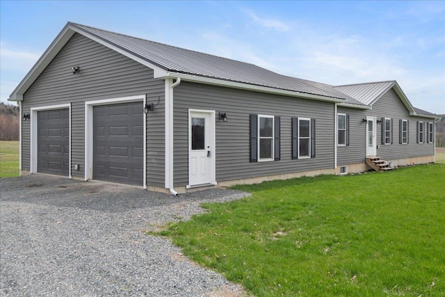 view of front of home featuring entry steps, a detached garage, metal roof, and a front yard