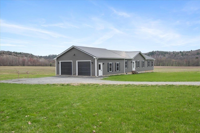 view of front of home featuring a view of trees, metal roof, gravel driveway, and a front yard