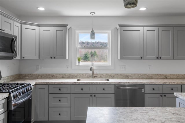 kitchen featuring gray cabinetry, appliances with stainless steel finishes, hanging light fixtures, and a sink