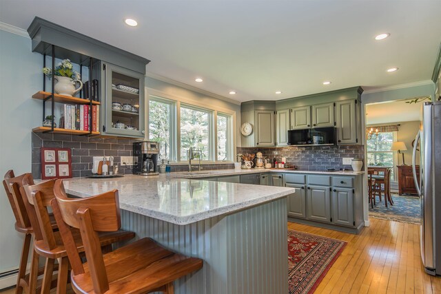 kitchen featuring crown molding, black appliances, a peninsula, and a healthy amount of sunlight