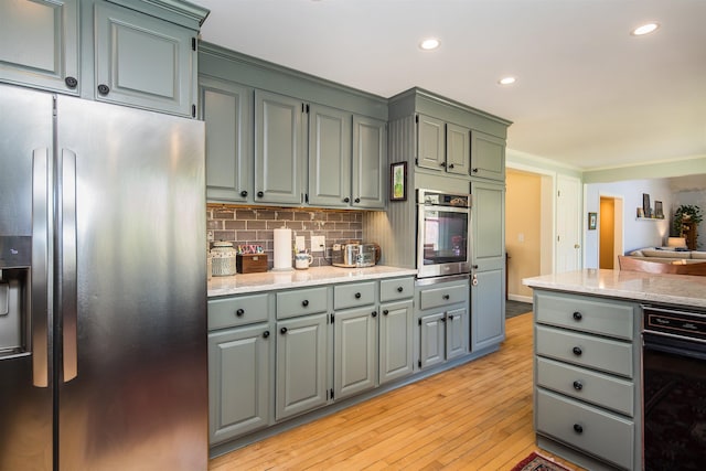 kitchen with light wood-style floors, appliances with stainless steel finishes, backsplash, and recessed lighting