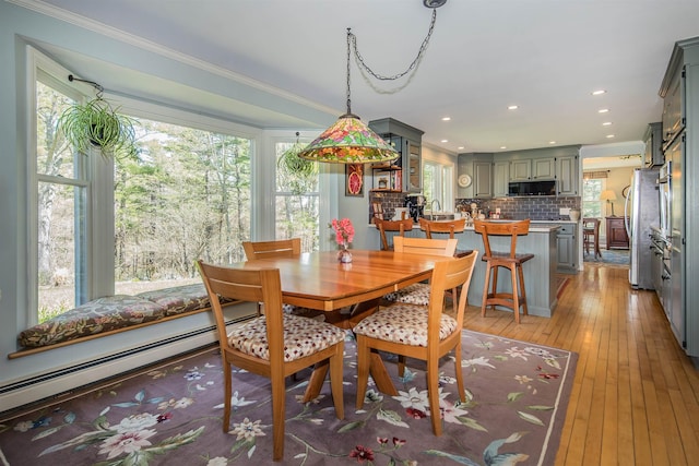 dining space featuring recessed lighting, a baseboard radiator, ornamental molding, and light wood-type flooring