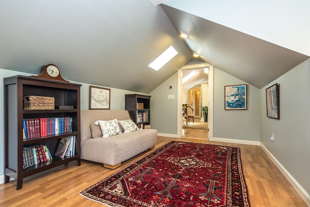 living area featuring baseboards, wood finished floors, and vaulted ceiling with skylight