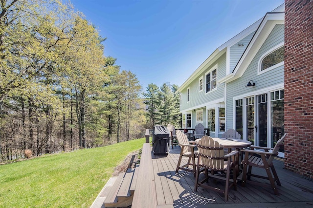 deck featuring outdoor dining area and a yard