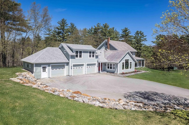 view of front of home with a chimney, roof with shingles, a garage, aphalt driveway, and a front lawn