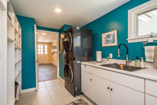 laundry area with stacked washer and clothes dryer, recessed lighting, a sink, cabinet space, and light tile patterned floors