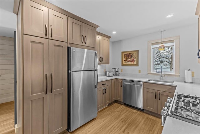 kitchen with a sink, light countertops, light wood-style floors, and stainless steel appliances