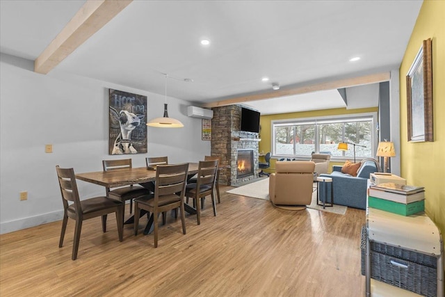 dining space featuring light wood-type flooring, recessed lighting, a wall mounted AC, and a stone fireplace