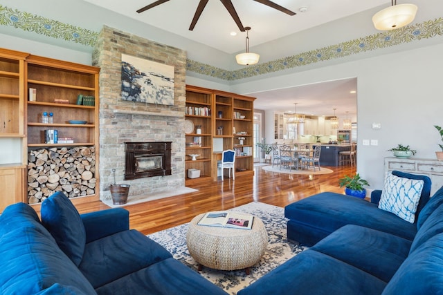 living area with ceiling fan, a fireplace, and wood finished floors