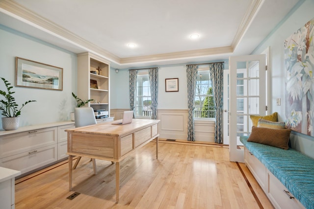 office with crown molding, a wainscoted wall, light wood-style flooring, and a raised ceiling