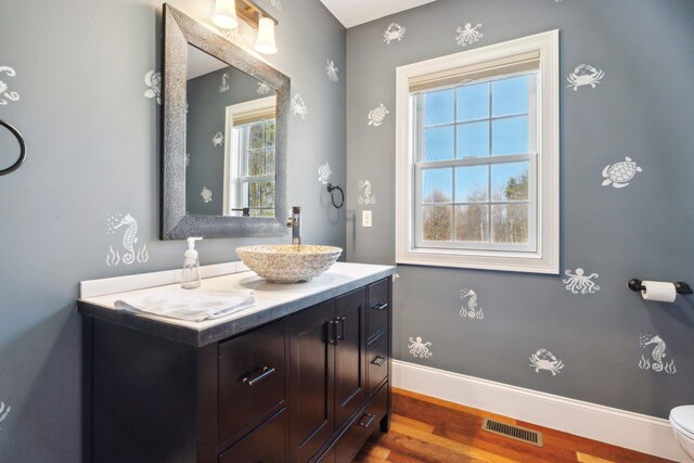 bathroom with visible vents, vanity, wood finished floors, toilet, and baseboards