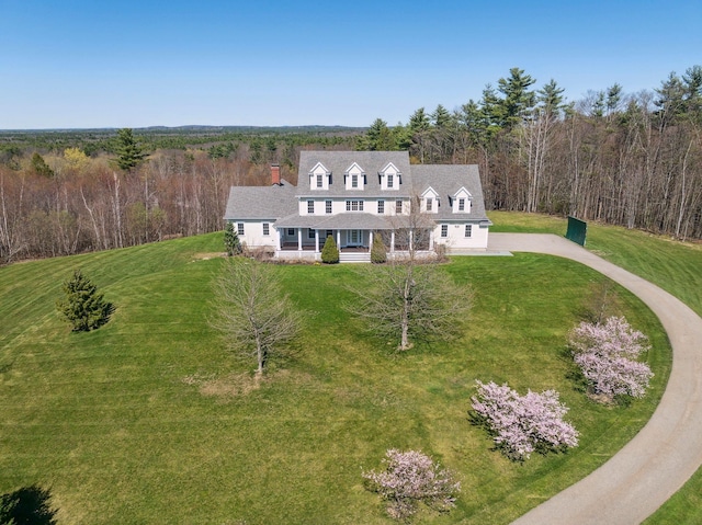 view of front of home with a porch, a forest view, and a front lawn