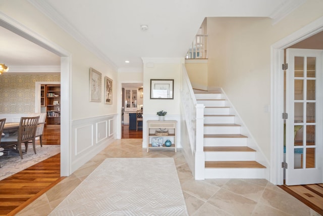 stairway with a decorative wall, ornamental molding, wainscoting, and recessed lighting