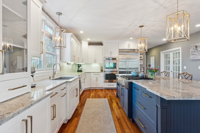 kitchen with stainless steel appliances, blue cabinetry, a notable chandelier, and a sink