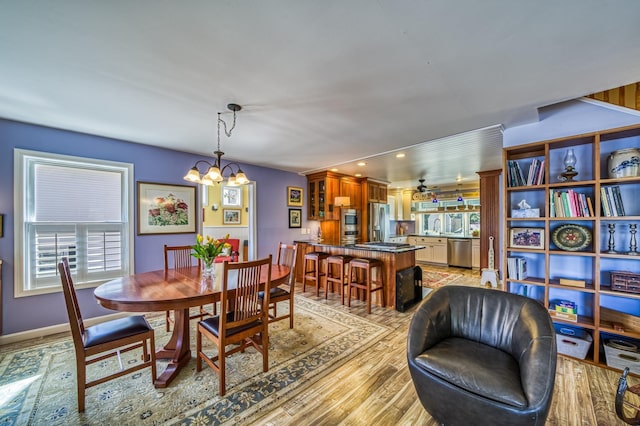 dining area with baseboards, light wood finished floors, and a notable chandelier